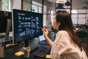 Female Analyst Reviewing Data on a Screen in Modern Office Setting