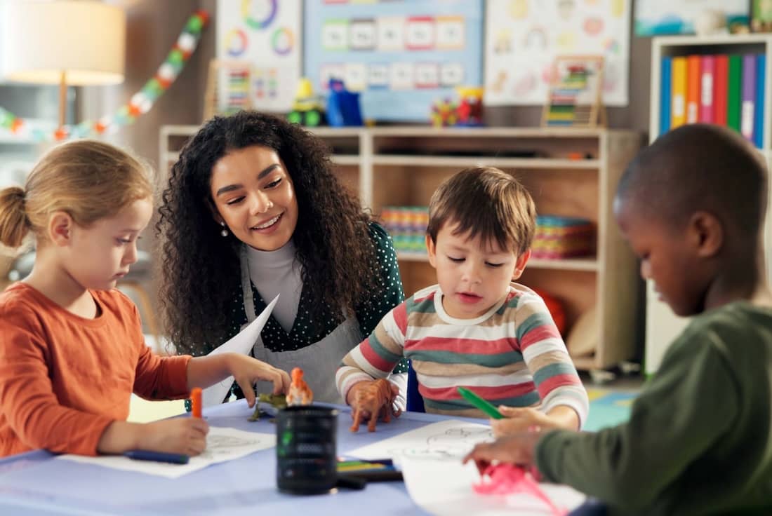 Teacher with children in classroom for learning, education and creative art.