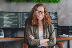 Female software developer sitting at workspace workstation indoors.