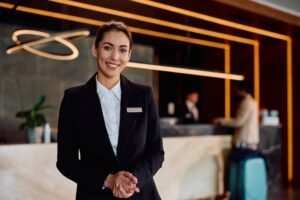 Smiling female hotel manager standing in front of the check in desk.