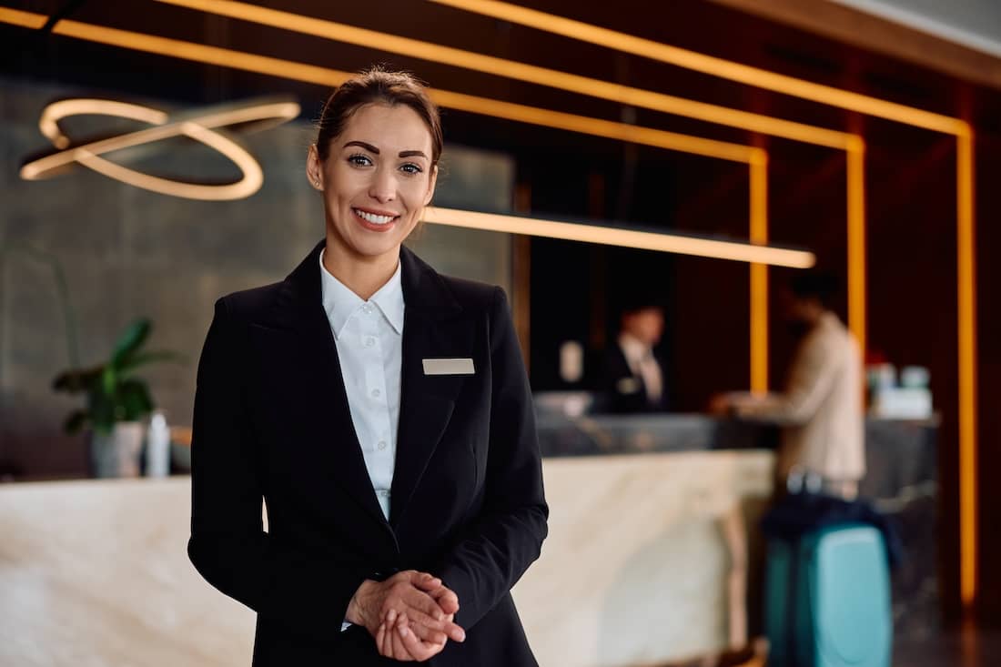 Smiling female hotel manager standing in front of the check in desk.