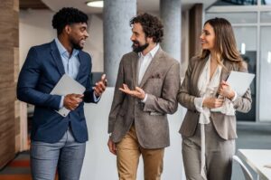 Three business professionals walking through a modern office building hallway.