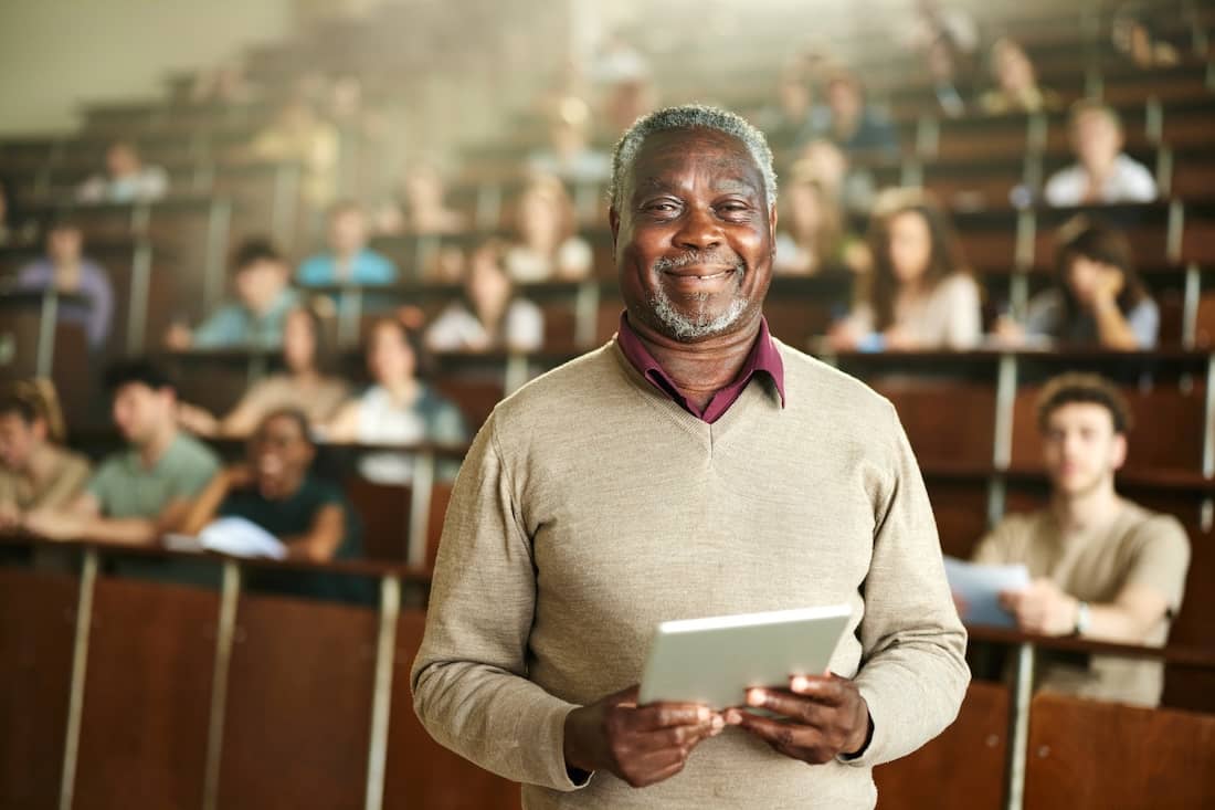 African American male professor working on digital tablet during a class in a lecture hall.